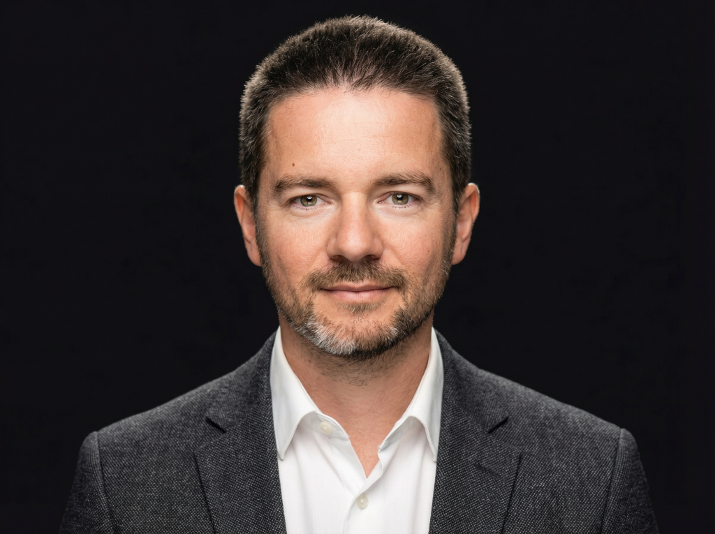 Владислав Наганов, деловой портрет с прямым взглядом на черном фоне