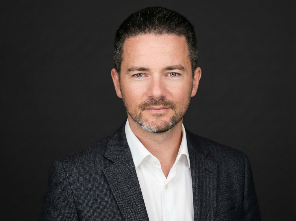 Владислав Наганов, крупный портрет в строгом костюме на темном фоне